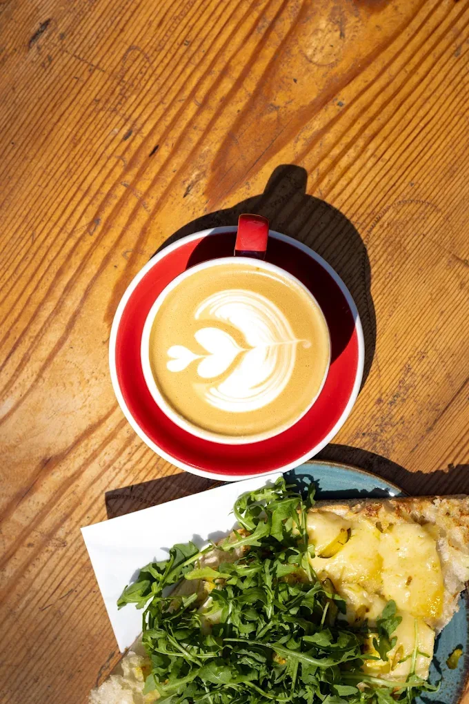 Flat White und ein Salatteller auf Holztisch