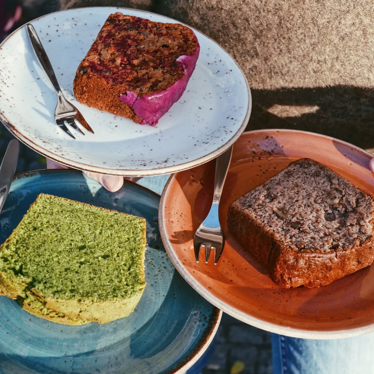 Drei Stücke hausgemachter Kuchen auf bunten Tellern